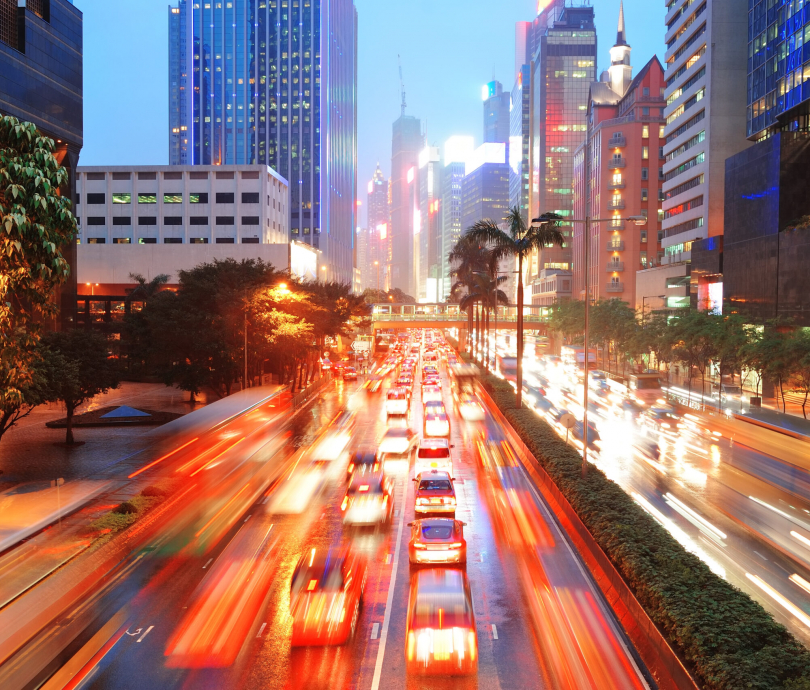 Hong Kong street with busy traffic and skyscraper office at dusk.